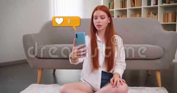 可爱的白种人红头发女孩在社交媒体上使用手机坐在室内的地板上喜欢的特写照片视频的预览图
