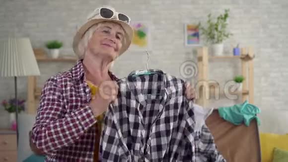 微笑着的老妇人正在度假在镜子前试着把衣服贴紧视频的预览图