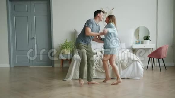 穿着睡衣的男女在卧室里跳舞笑着欣赏音乐视频的预览图