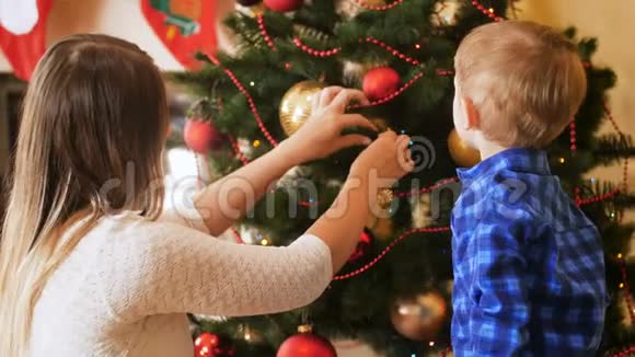 小男孩和妈妈在客厅装饰圣诞树的4K镜头冬季家庭装饰屋视频的预览图