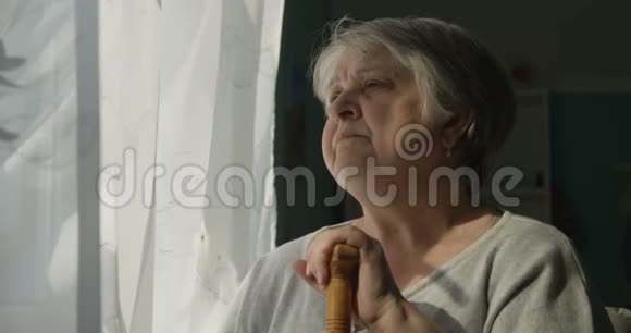 悲伤的老年妇女看窗烟的肖像忧郁孤独的概念视频的预览图
