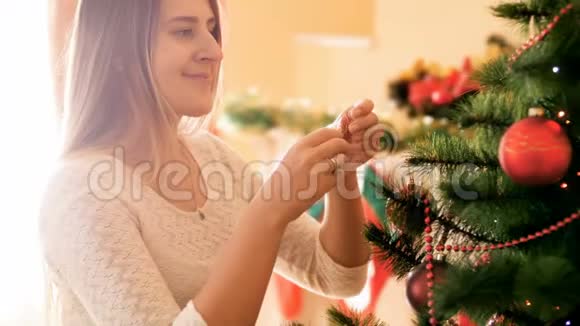 在客厅的圣诞树上挂着长头发的美丽微笑的女人的4K视频家庭视频的预览图