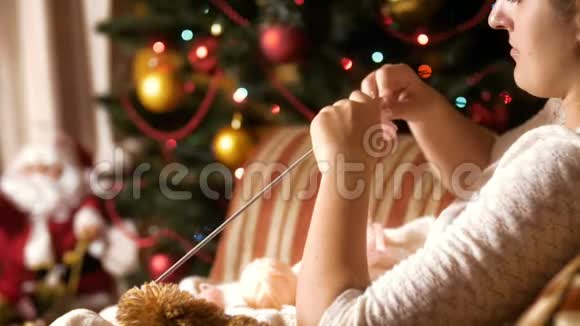 4K镜头美丽的年轻女子坐在扶手椅旁边装饰圣诞树和针织羊毛袜子人民视频的预览图