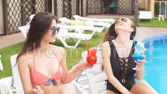 两个漂亮的女孩喝着五颜六色的鸡尾酒视频的预览图