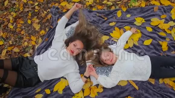 妈妈和女儿躺在秋天森林的地上视频的预览图