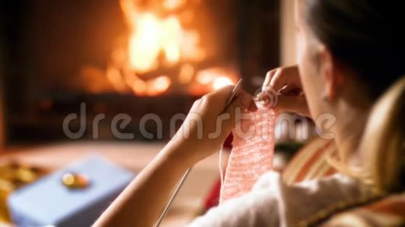 为孩子们准备的女织羊毛围巾的特写镜头她坐在家里燃烧的壁炉旁视频的预览图