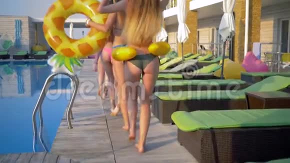 快乐的朋友女孩穿着带充气戒指的泳衣在度假的泳池边玩得开心视频的预览图