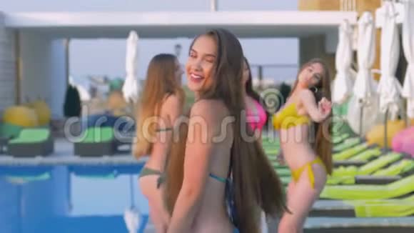 长头发的快乐女朋友在假日期间在昂贵的度假胜地泳池边穿泳装跳舞视频的预览图