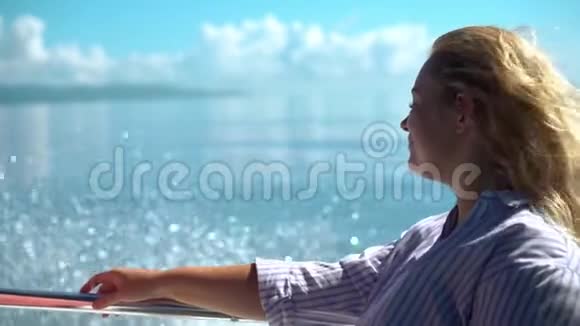 美丽的金发女人享受阳光和水的飞溅同时在船上旅行她头发上的风视频的预览图