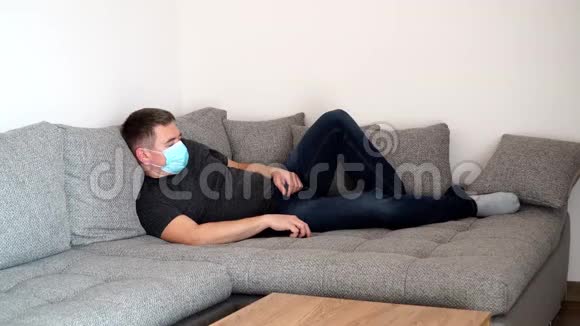 被隔离的冠状病毒男子戴着医疗面具很累睡在沙发上COVID19视频的预览图