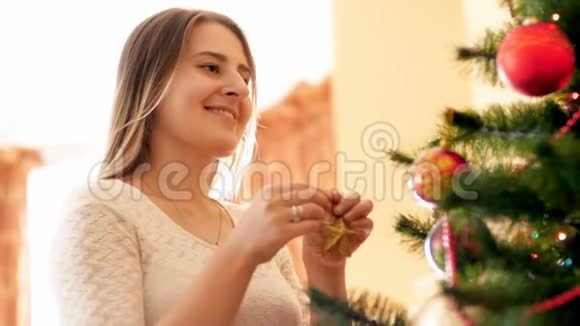 美丽的微笑的女人站在大窗户前挂在圣诞树上的鲍布家庭视频的预览图
