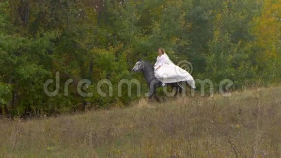 穿着白色衣服的年轻女子骑着马在木头附近视频的预览图