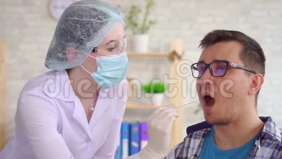 女实验室技术人员用棉签从一个男人嘴里取出唾液视频的预览图