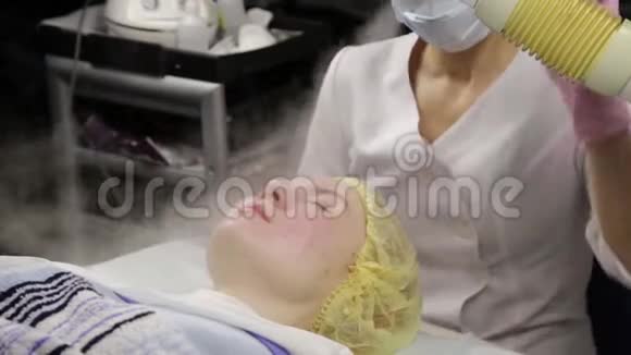 医生用蒸汽清洗那女人的皮肤美容师皮肤有问题的年轻女人宇宙学概念视频的预览图