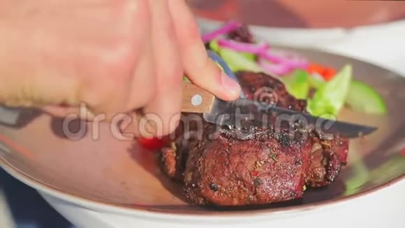 在盘子上切出多汁的新鲜烤肉男人街上切下一块肉视频的预览图