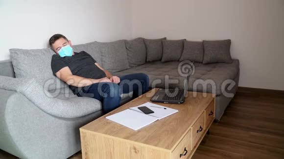 戴医疗面具的商人厌倦了工作在工作场所睡觉检疫冠状病毒COVID19距离工作视频的预览图