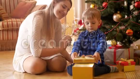快乐微笑的小男孩在圣诞节打开他的礼物盒并向他的母亲展示礼物的视频家庭捐赠视频的预览图