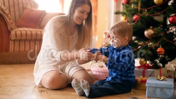 一家人在圣诞树下坐在地板上玩和扔纸屑的4k视频家庭成员视频的预览图