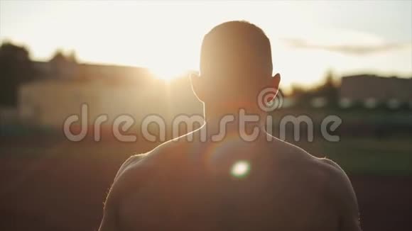 慢动作英俊的赤膊青年走向镜头的肖像身后有灿烂的阳光视野模糊视频的预览图