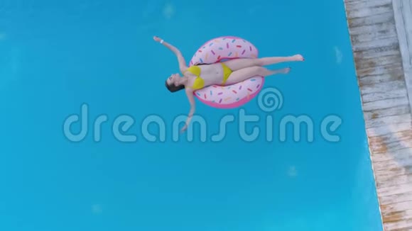 夏季放松周末在昂贵的度假胜地的游泳池里迷人的女人穿上泳衣漂浮在充气环上视频的预览图