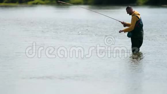 渔夫扔了一个浮子手牵着一条鱼站在河里视频的预览图