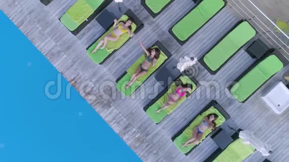 夏季休息快乐性感的女朋友穿上泳衣在昂贵的度假胜地游泳池附近的休息室放松视频的预览图