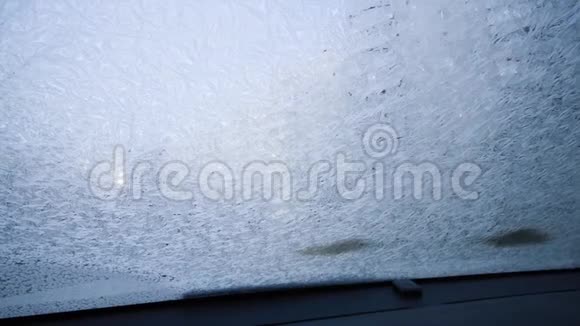 转动你的冰刮板同时从你的雪覆盖汽车的窗户上移除厚厚的冷层冰视频的预览图