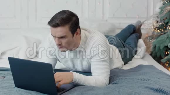 专心致志的男人躺在豪华的床上躺着电脑视频的预览图