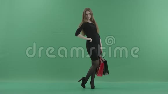 美丽快乐的女人穿着黑色的小裙子摆着姿势用购物袋旋转笑着她是视频的预览图