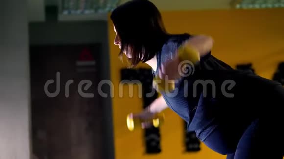 年轻的孕妇一个大肚子穿着黑色运动服正在用哑铃做手臂练习视频的预览图