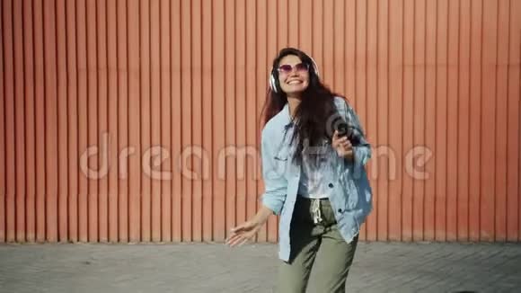 戴着墨镜和耳机在户外跳舞的快乐亚洲女孩视频的预览图