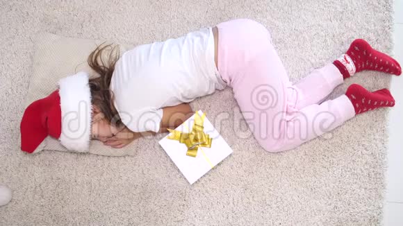 顶级视频的小女孩戴着圣诞帽睡在她身边的圣诞礼物视频的预览图