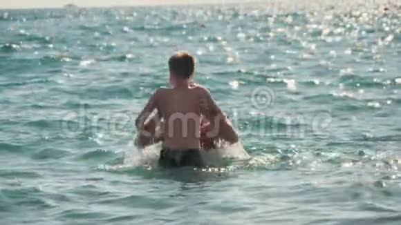 爸爸和儿子在海里游泳和玩耍他们休息享受生活慢动作视频的预览图