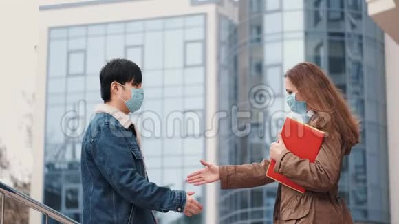 中国男人和一个戴一次性口罩的女人握手视频的预览图