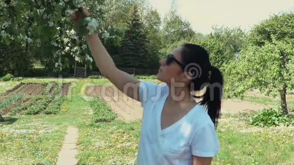 花园里开花的苹果树上的女人视频的预览图