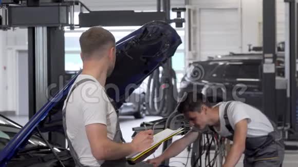 两个机械师在车库里讨论修理坏了的汽车视频的预览图