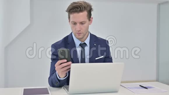 专业的年轻商人在手提电脑和使用智能手机视频的预览图