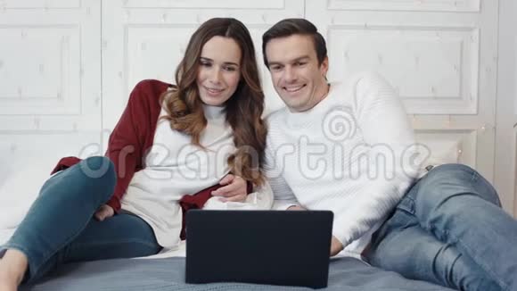 幸福的一家人在客厅的笔记本电脑屏幕前大笑视频的预览图