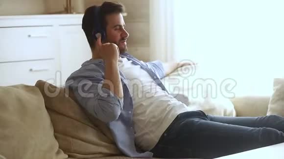 戴着耳机的男人躺在沙发上弹假吉他视频的预览图