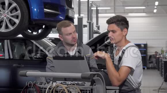 两名汽车修理工在车库用笔记本电脑进行汽车诊断视频的预览图
