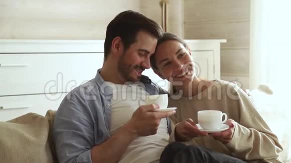 可爱的一对恋人坐在沙发上喝茶视频的预览图