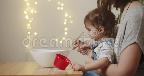 可爱的蹒跚学步的女孩帮妈妈做饼干视频的预览图