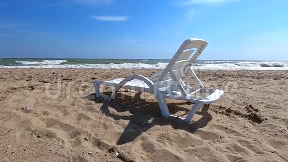 白色塑料日光浴床矗立在海边的沙滩上视频的预览图