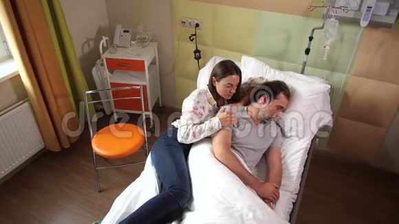 心烦意乱的妻子躺在床上躺在生病的熟睡的丈夫身边视频的预览图