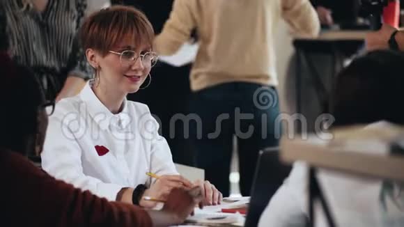 中镜头的快乐年轻白种人商务女性与美丽的害羞微笑工作在多民族现代阁楼办公室视频的预览图