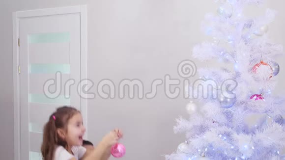 小女儿想把粉红色的宝布尔挂在树的顶端所以爸爸把她抱起来孩子做她做的事视频的预览图