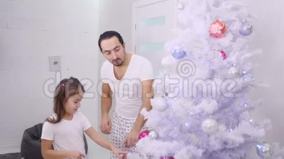 小女儿想把粉红色的宝布尔挂在树的顶枝上所以爸爸挑选她然后他们拥抱着她视频的预览图