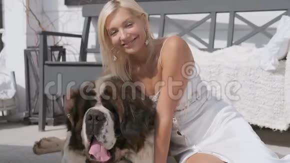 一个年轻的女孩抱着一只大狗坐在房子附近的门廊上微笑肖像视频的预览图
