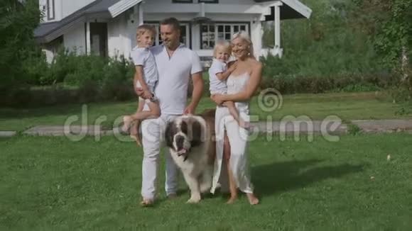 幸福的四口之家在房子附近的草地上遛狗视频的预览图