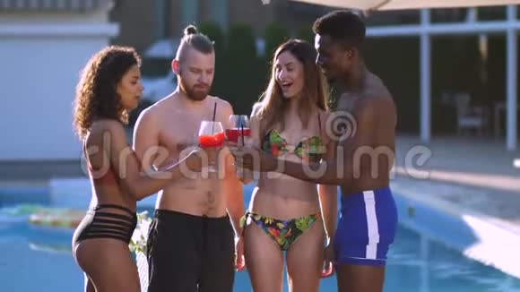 多种族的快乐朋友在泳池边喝果汁视频的预览图